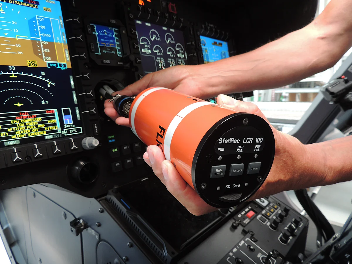 Nahaufnahme zweier Hände, die einen Light Weight Flight Recorder im Cockpit einbauen.
