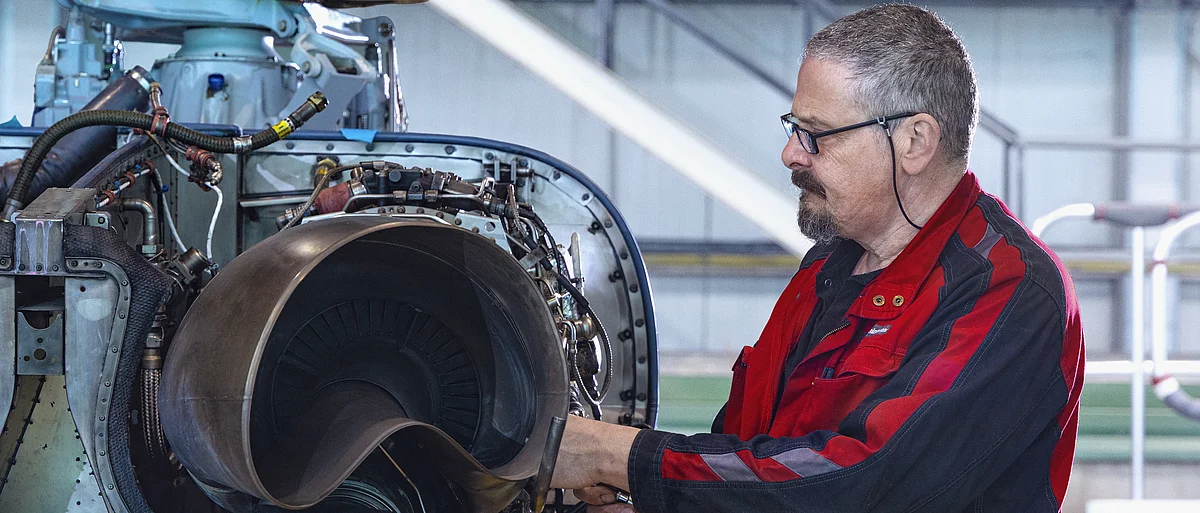 Eine Fluggerätmechaniker arbeitet an einem Triebwerk eines Hubschraubers.