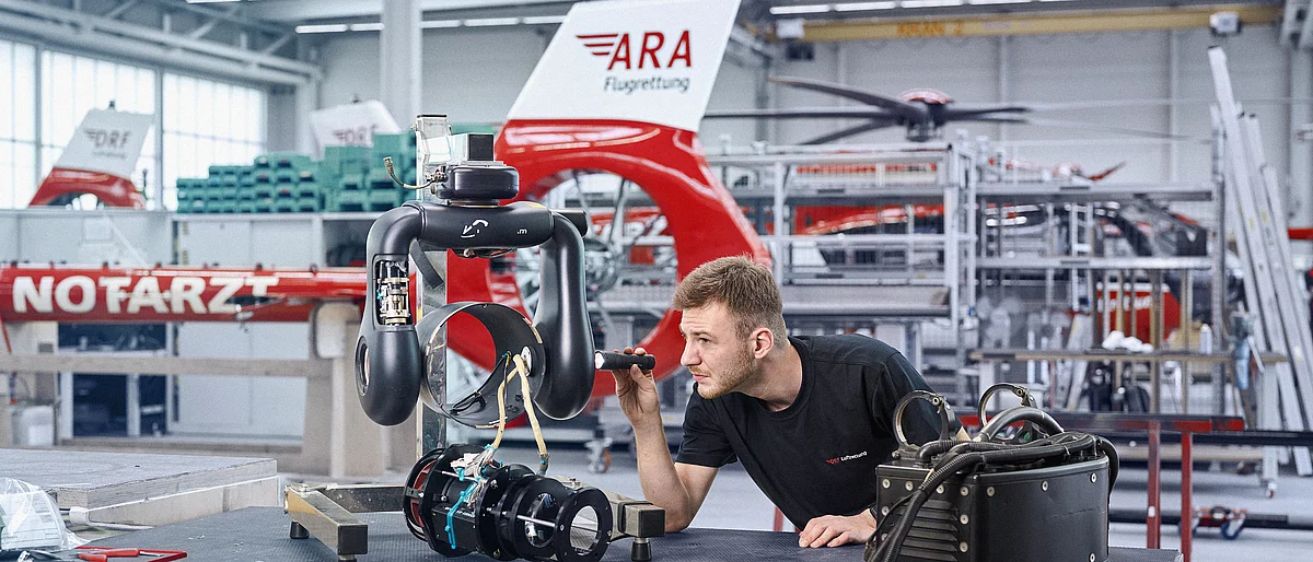 Ein Techniker prüft einen Hochleistungsscheinwerfer eines Hubschraubers.