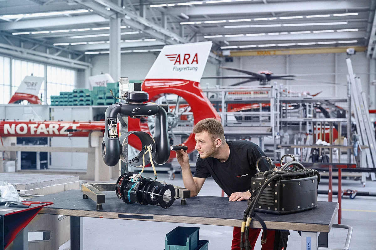 Ein Techniker prüft einen Hochleistungsscheinwerfer eines Hubschraubers.